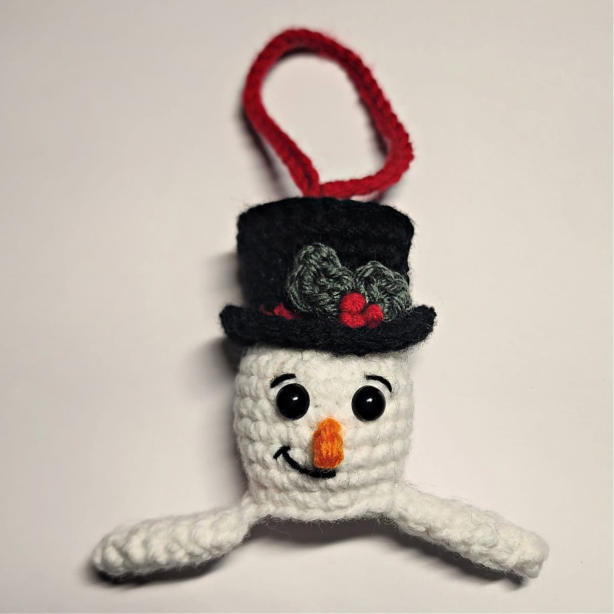 Top half of crochet snowman complete with facial features and ornament hanging loop.