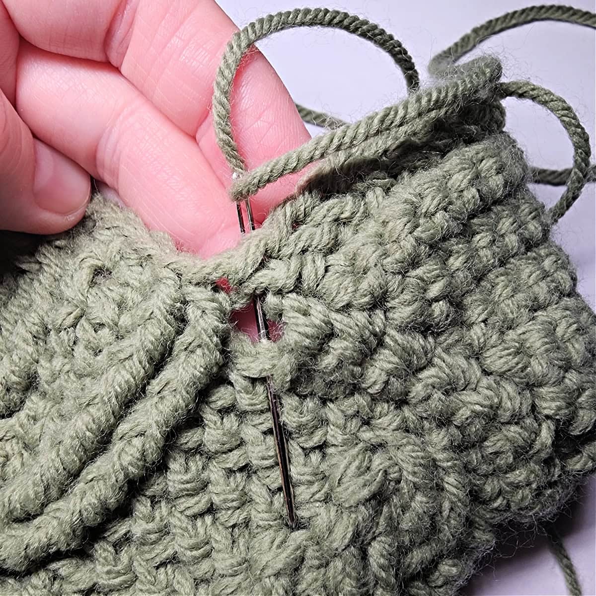 A yarn needle showing how to sew the gap in the heel closed.