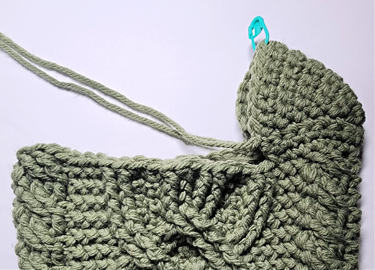 Side view of a short row heel on a green cabled stocking.