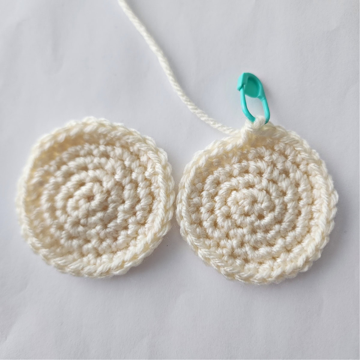 Teo cream colored crochet circles one of them with a locking stitch marker.