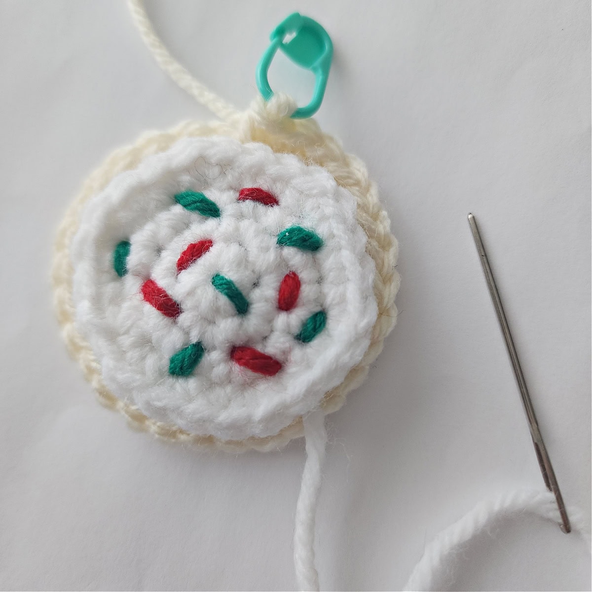 Crochet frosting being sewn onto a crochet sugar cookie.