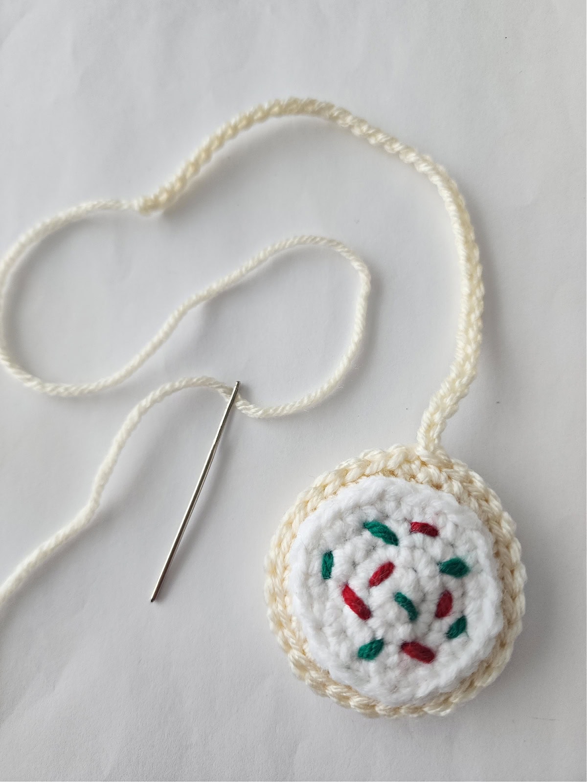 Crochet Christmas cookie ornament with one end of the hanging loop not yet attached.