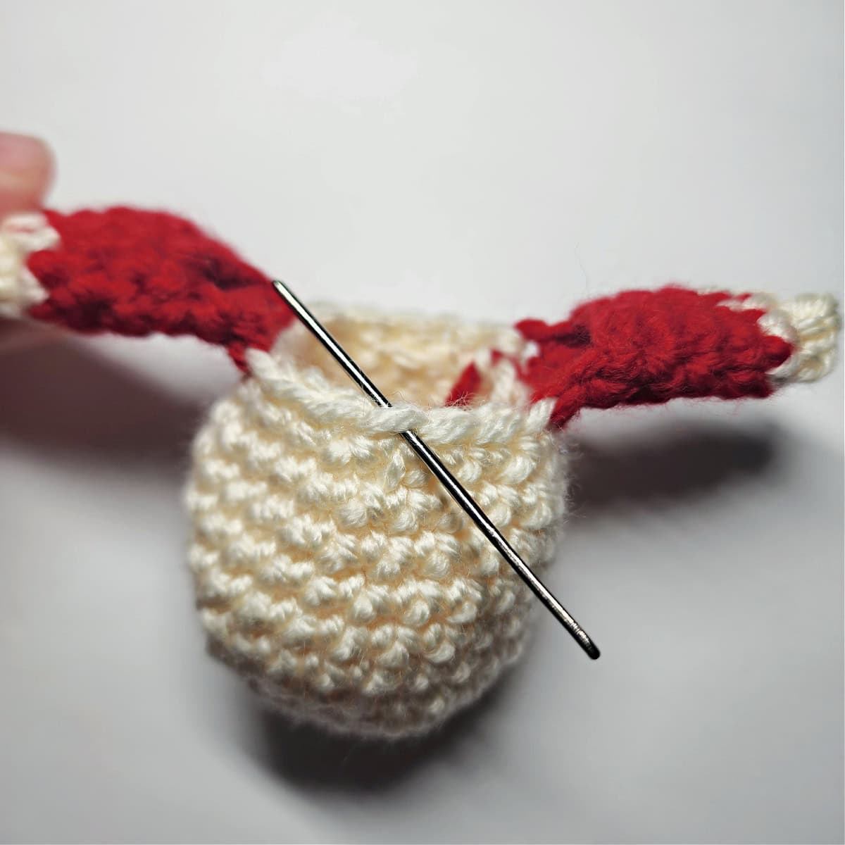 A yarn needle showing where to attach yarn to begin the girl elf's crochet collar.