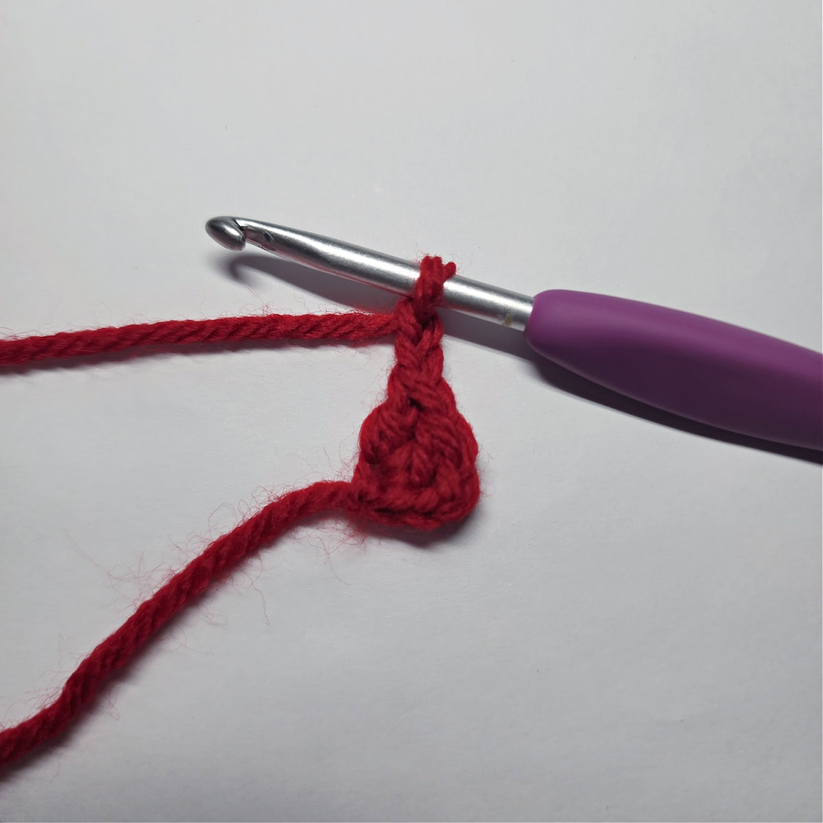 Beginning of a mini crochet bow with a purple crochet hook.