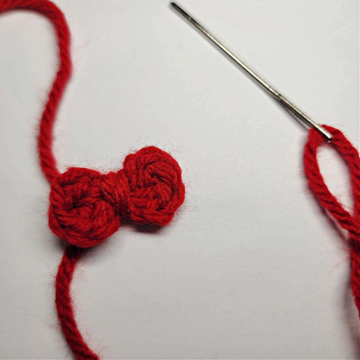 A mini crochet bow made as a hair bow for a gingerbread girl.