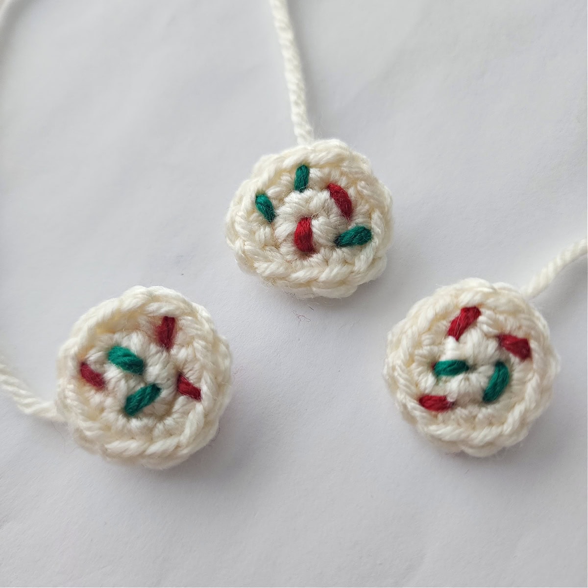 Three mini crocheted sugar cookies with sprinkles.