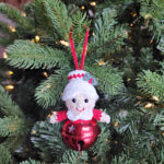 Crochet Mrs Claus jingle bell ornament hanging on a Christmas tree.