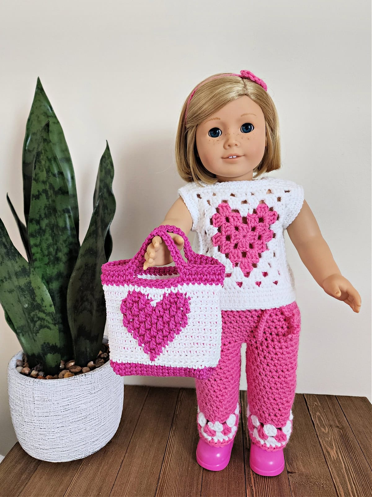 18" doll wearing crochet doll clothes and holding a small Valentine's treat bag.