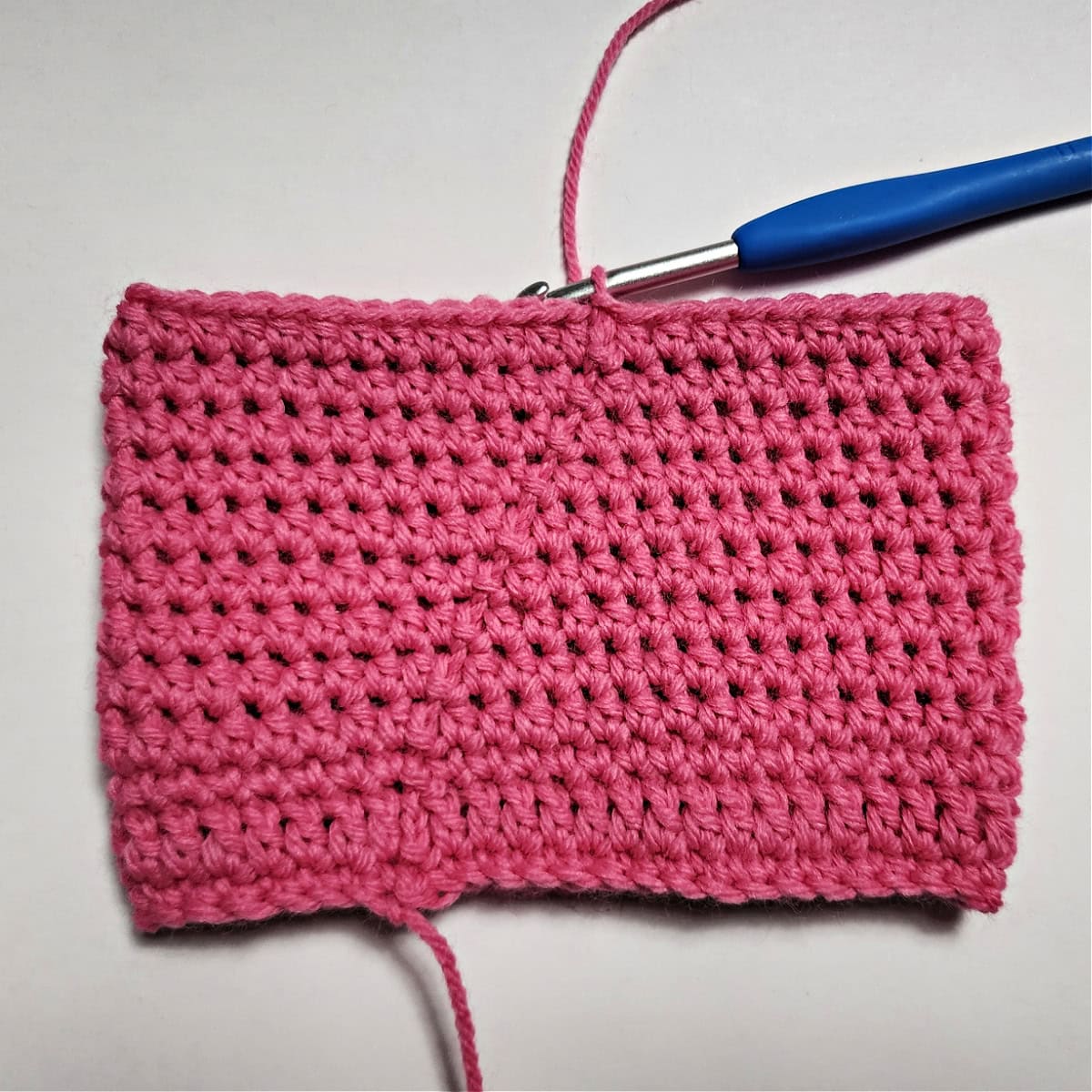 The beginning of a pair of pink crochet doll pants.