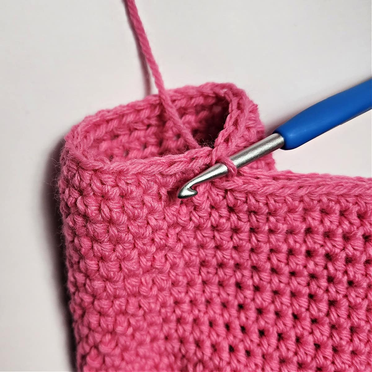 A crochet hook showing how to create the first leg on a pair of crochet doll pants.