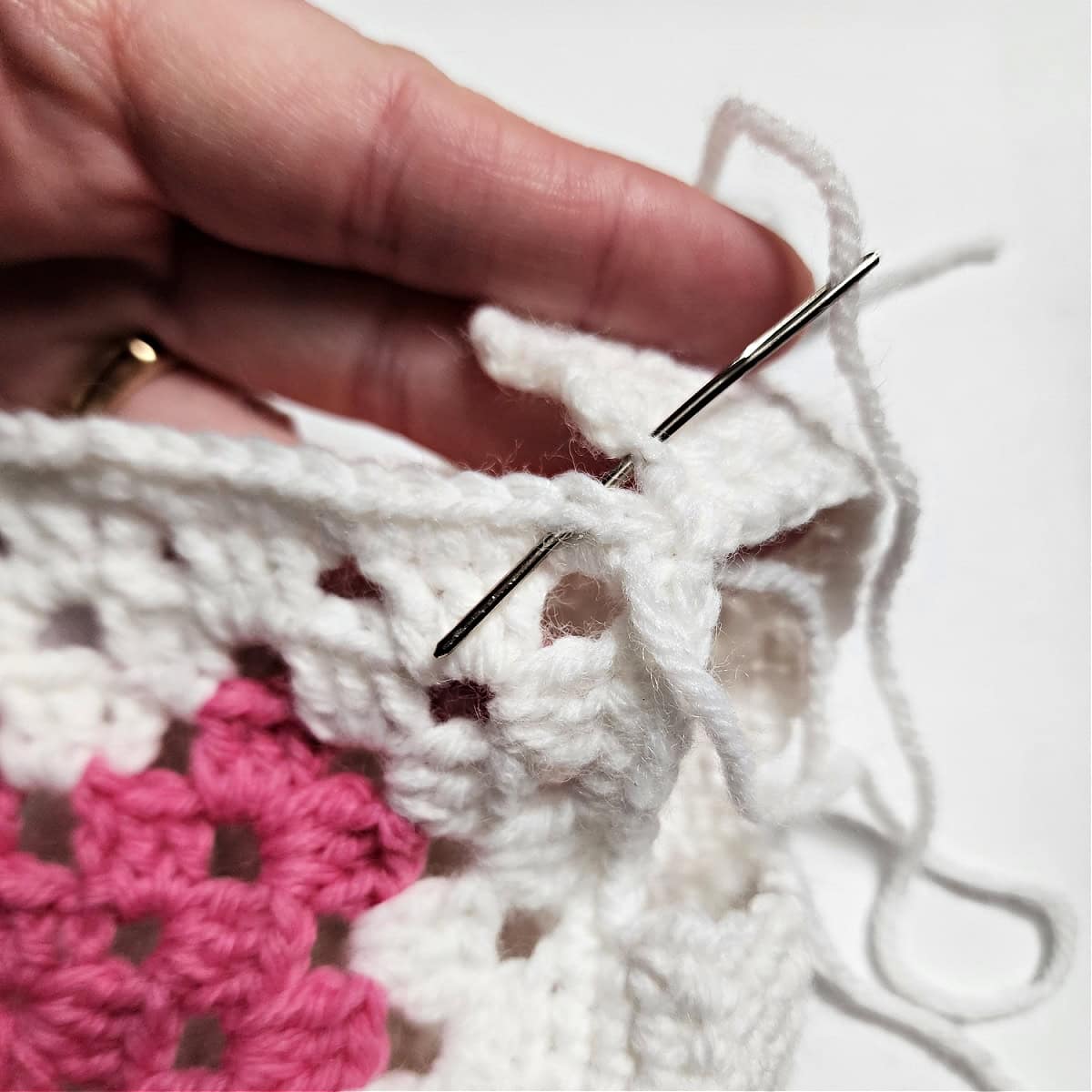 A yarn needle showing how to whipstitch the shoulder seams on the crochet doll top.