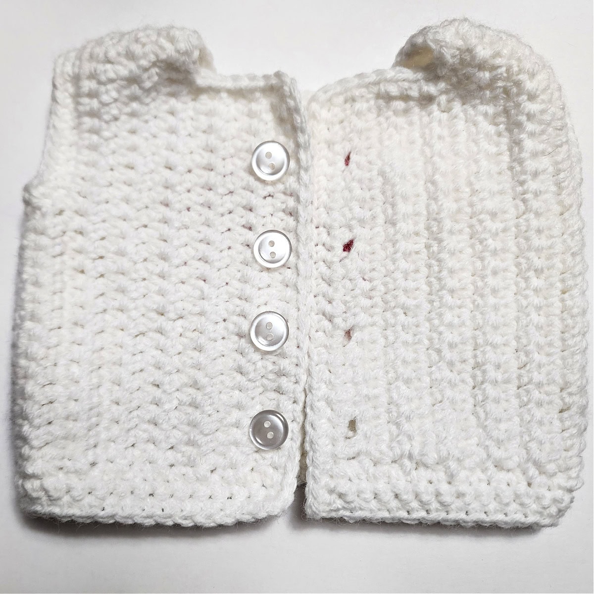 This photo shows how to line up the buttons with the buttonholes on the crochet doll sweater.