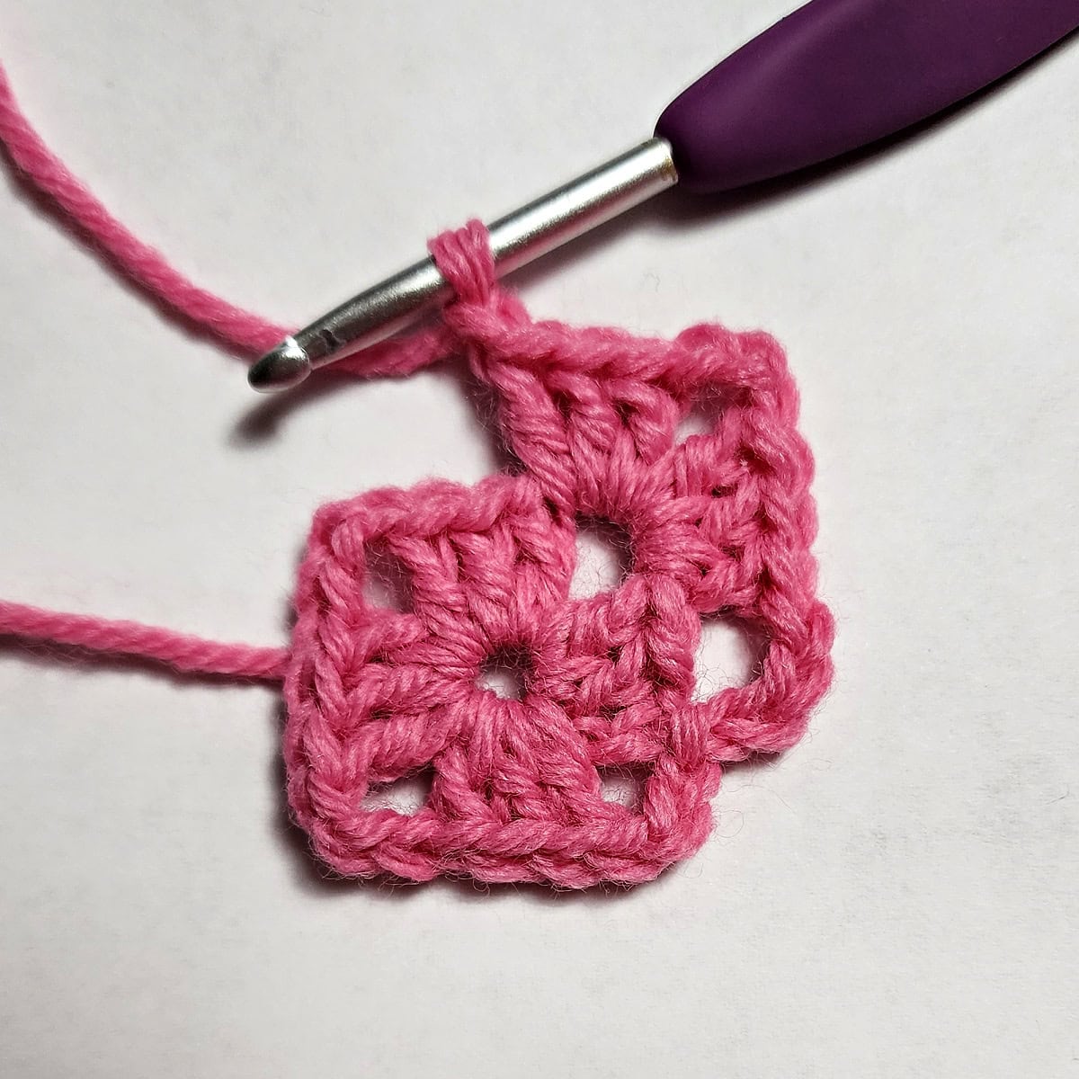 Round two being crocheted of a crochet heart granny square.