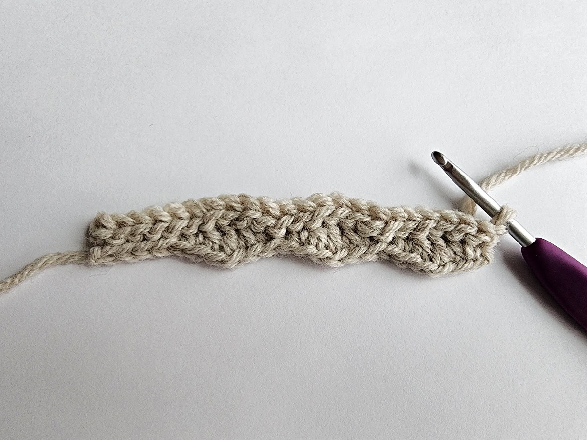 The beginning of row 3 of a slipper cuff in a knit-look crochet stitch pattern.