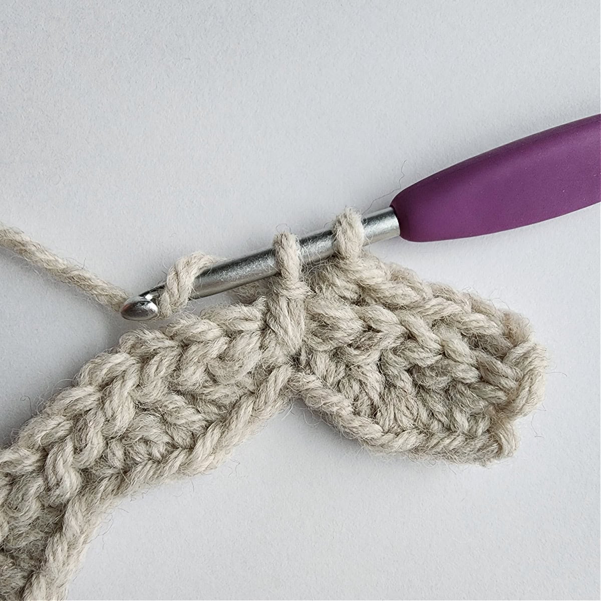 A long double crochet worked two rows down in a knit-look crochet stitch pattern.