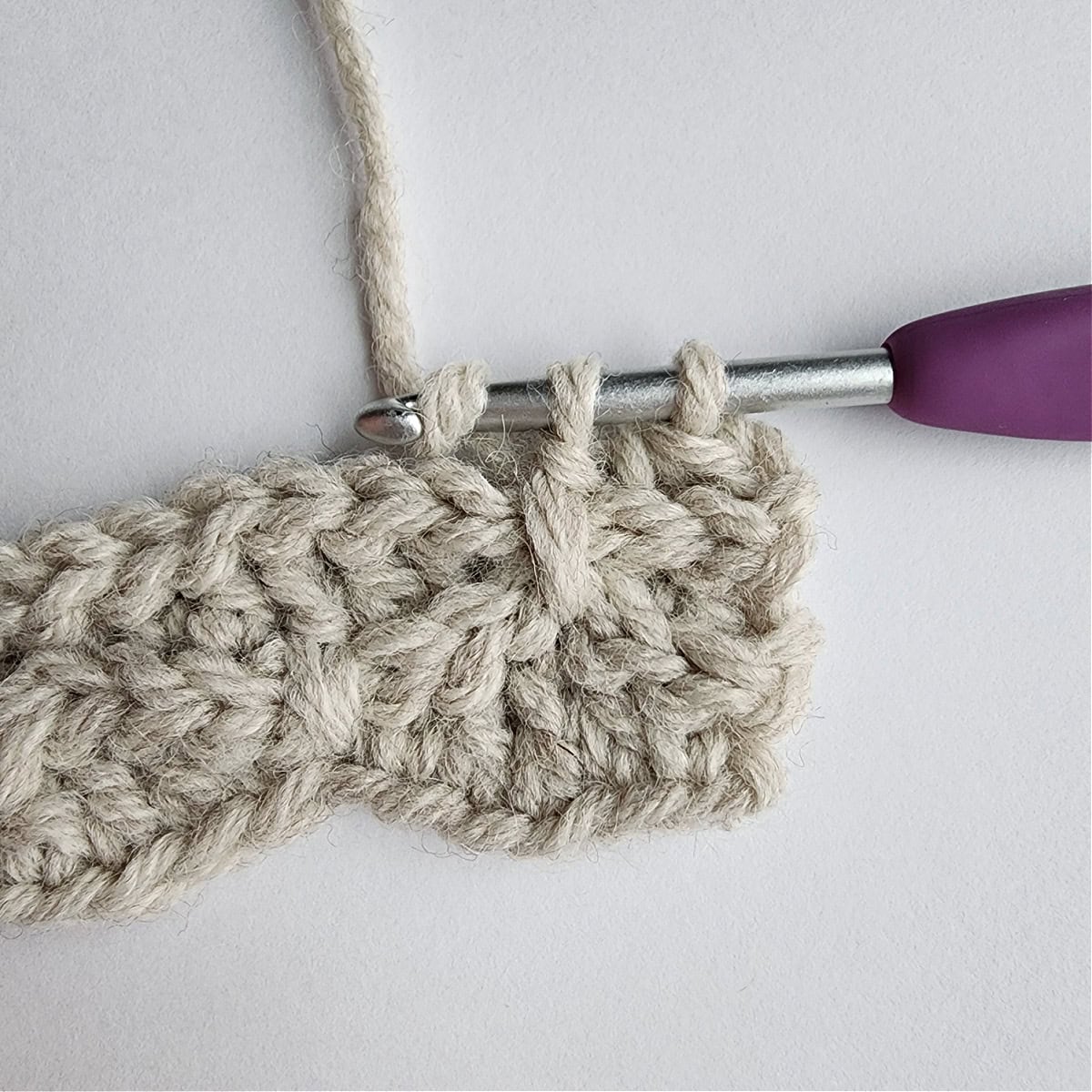 Close-up photo showing where to work the first long double crochet in row 5.