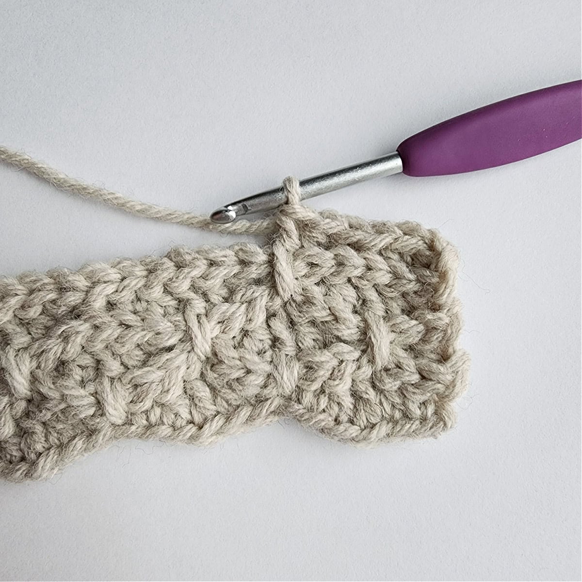 The first long double crochet worked in row 7 of the mock smock crochet stitch pattern.