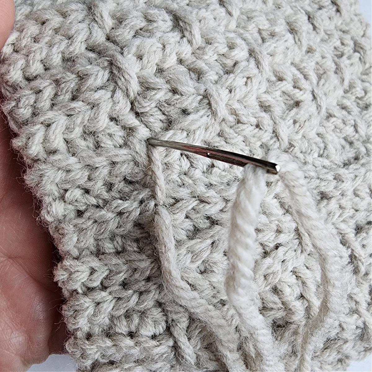 Insert the yarn needle through the same stitch to complete the first finishing stitch.