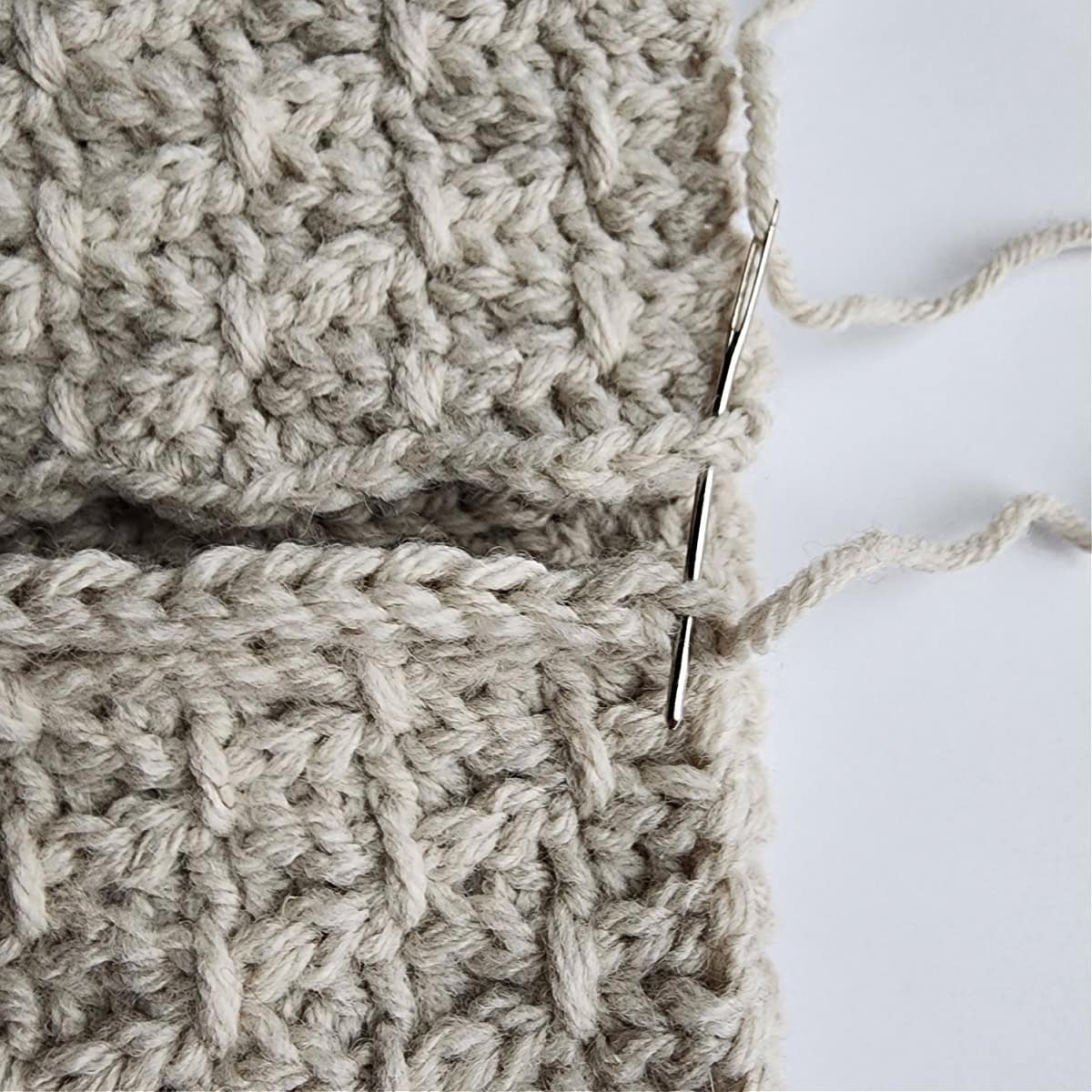 A close-up showing which loops the yarn needle is inserted through to seam the slipper cuff.