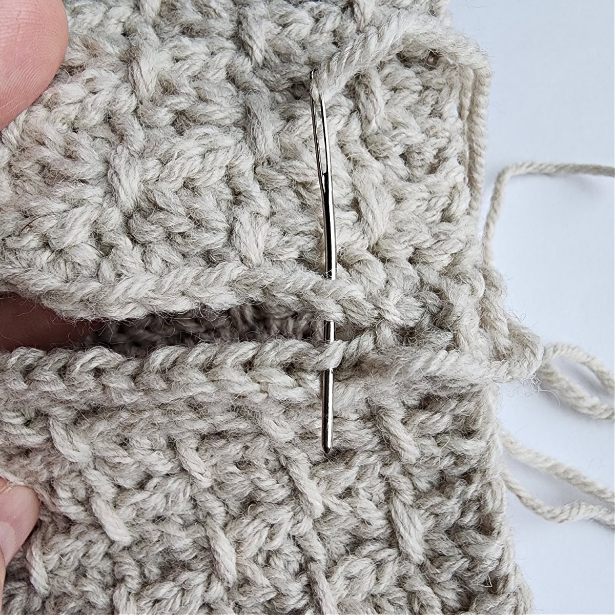 Use a yarn needle to whipstitch both loops of the first row to the back loops only of the last row.