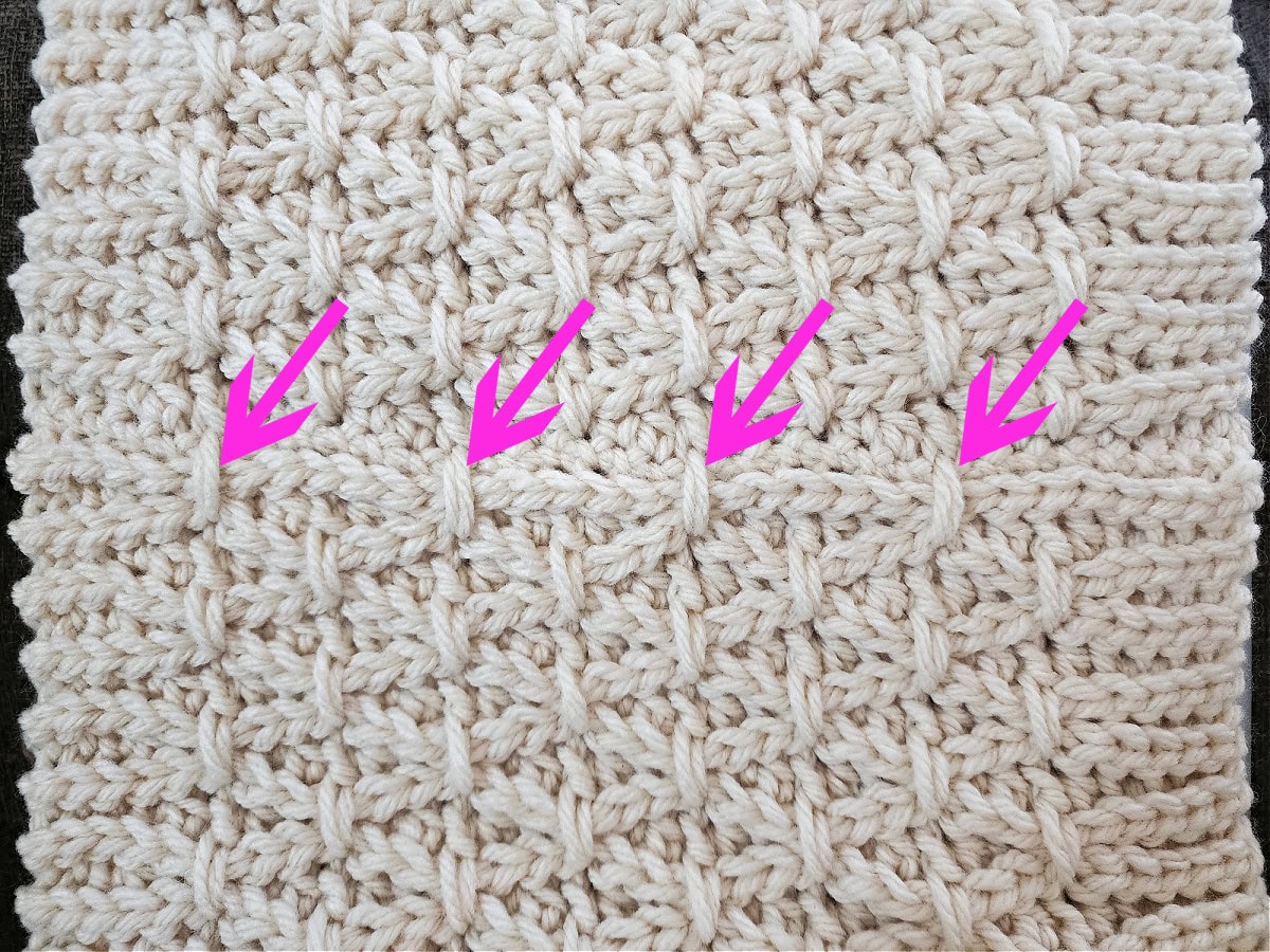 Four pink arrows pointing at the finishing stitches created on a cowl seam.