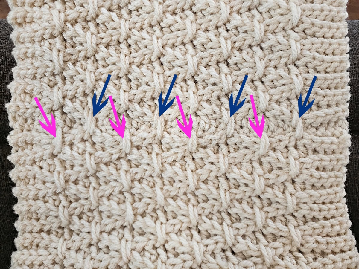 A set of pink and blue arrows pointing to all of the finishing stitches used to blend the seam of the free crochet cowl pattern.