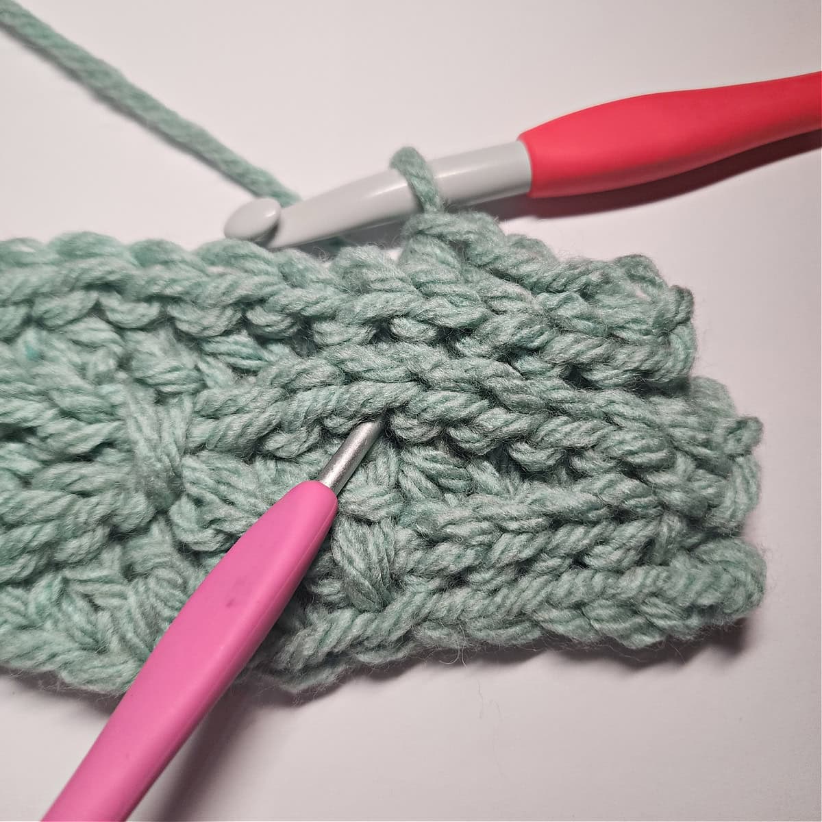 The purple crochet hook shows where to work the dc into the next dc 4 rows below.