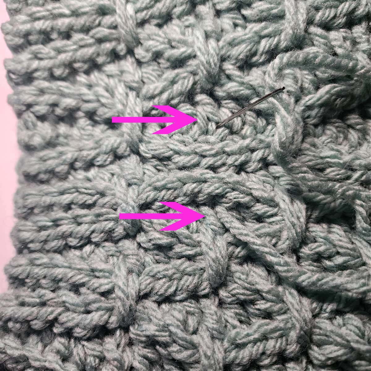 Two pink arrows pointing to the stitches where the next set of finishing stitches will be worked.