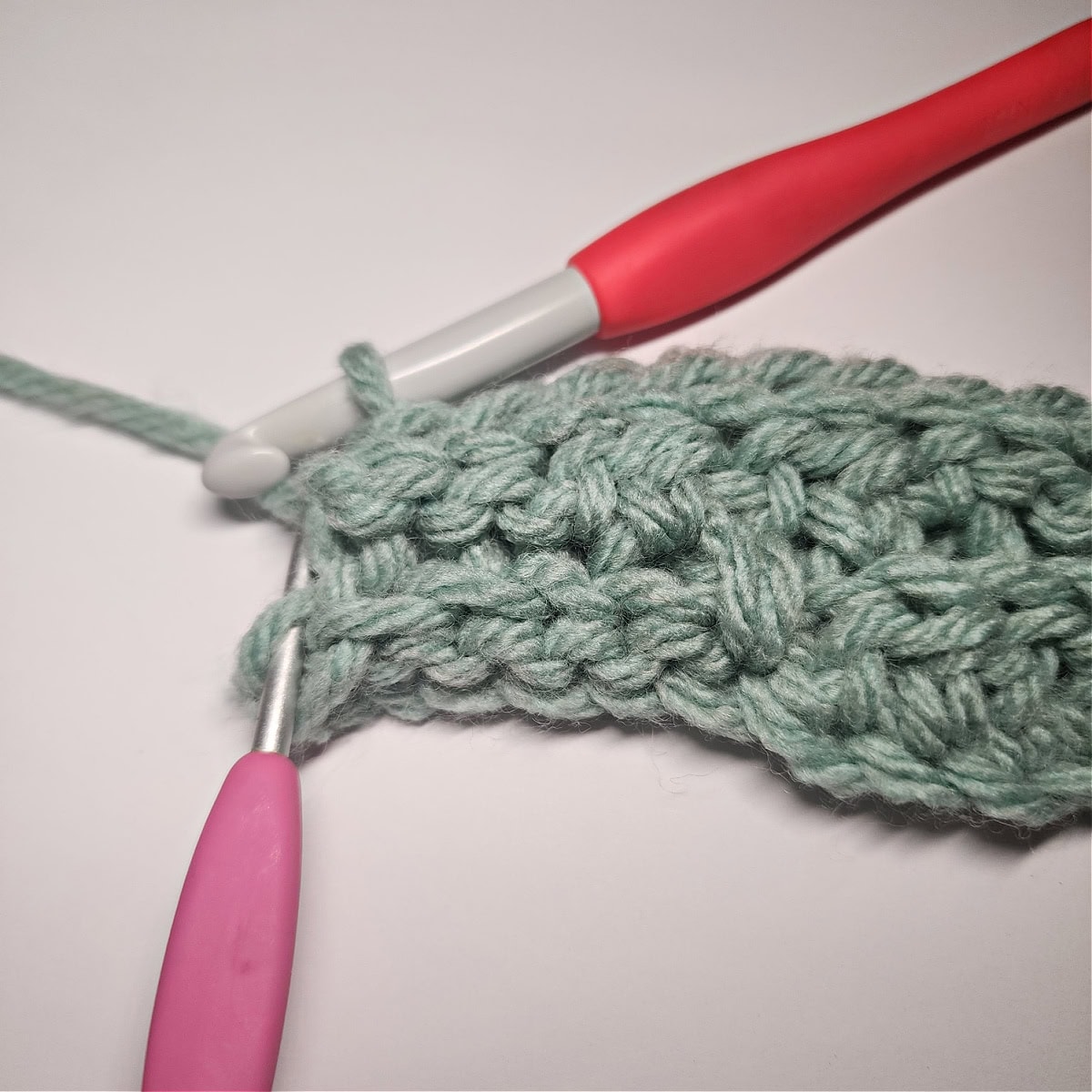 A pink crochet hook showing where to work the last slip stitch of the row into the short row.