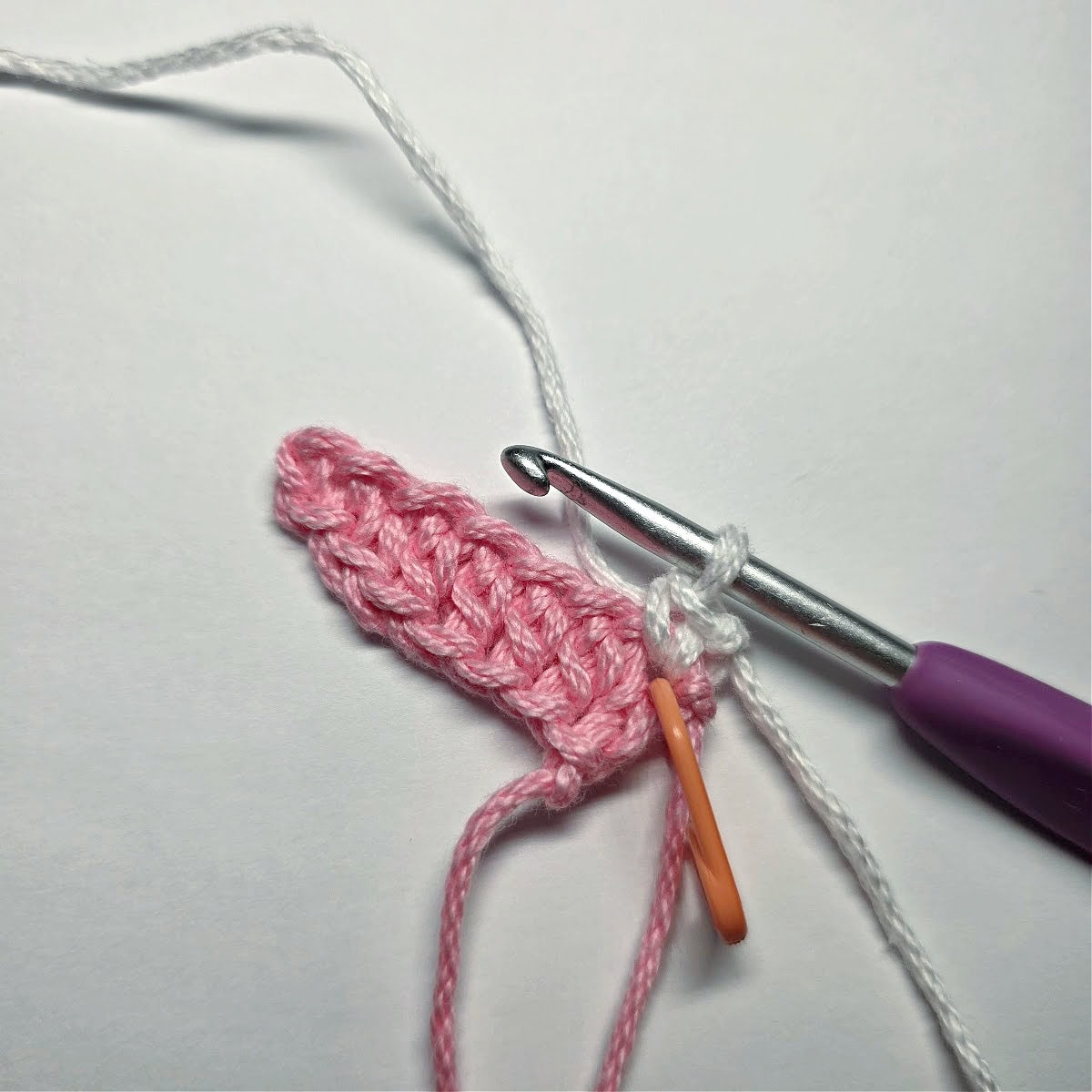 White yarn crocheting the outer edge of a crochet bunny ear.