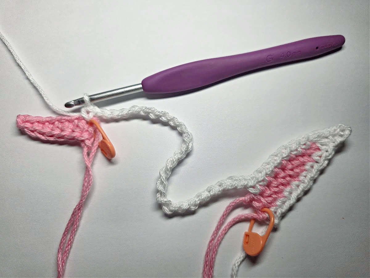 White yarn being used to connect two crochet bunny ears.