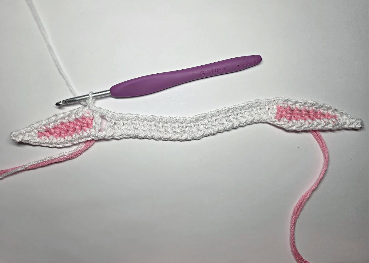 Crochet bunny ears napkin ring in white and pink.