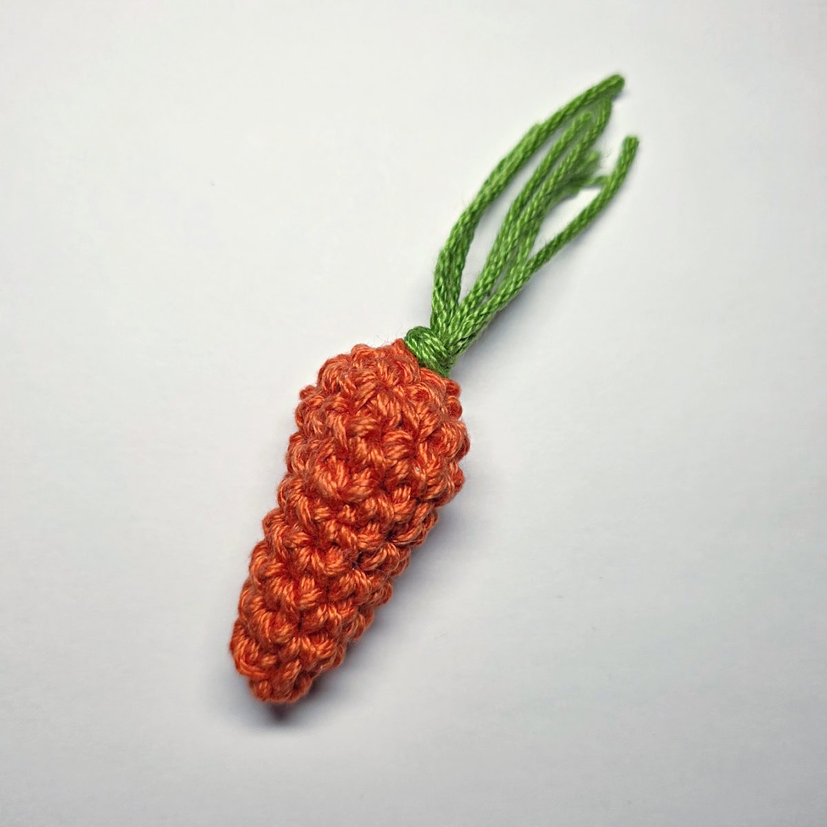 A green carrot top added to a crochet carrot before being trimmed.