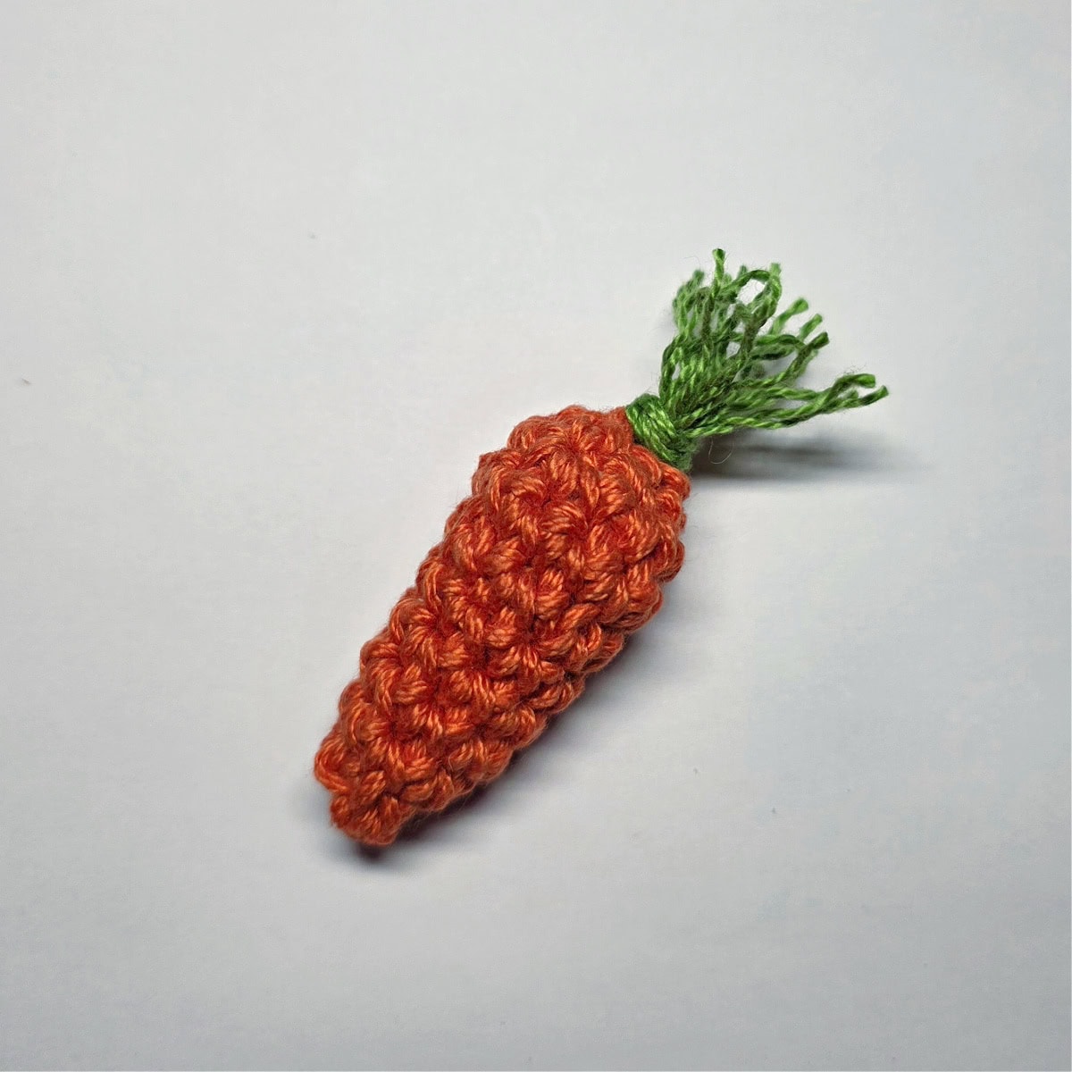 Crochet carrot with trimmed carrot top.