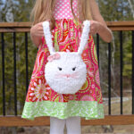 A young girl in a paisley spring dress holding a crochet Easter treat bag.