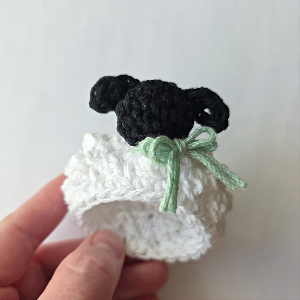 A side view of a crochet lamb napkin ring.