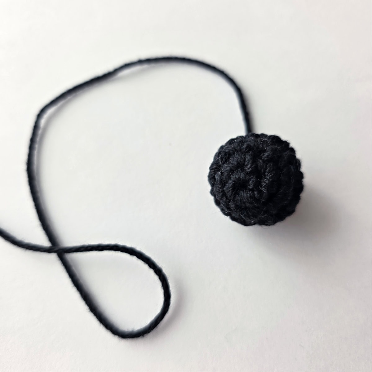 A small black crochet ball that will become a lamb's head.