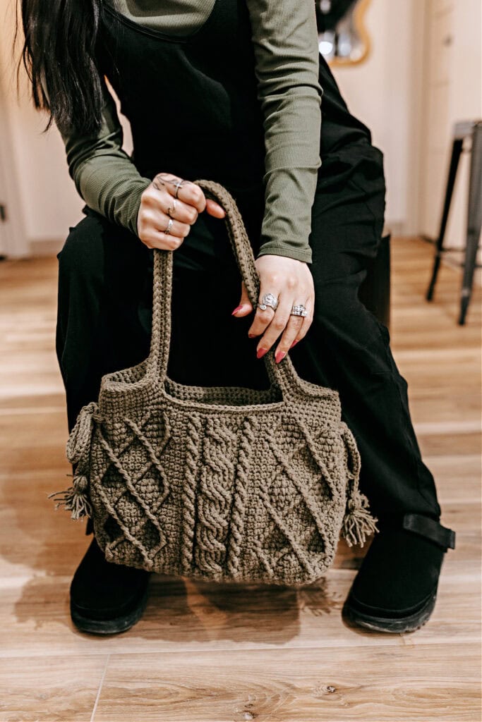 Close-up of a crochet purse with yarn straps and cables.