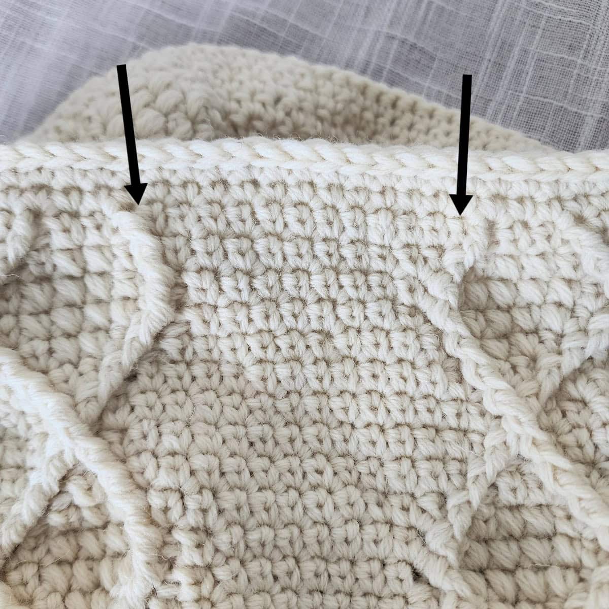 Two black arrows pointing to the set of stitches that you'll work a crochet pleat over.