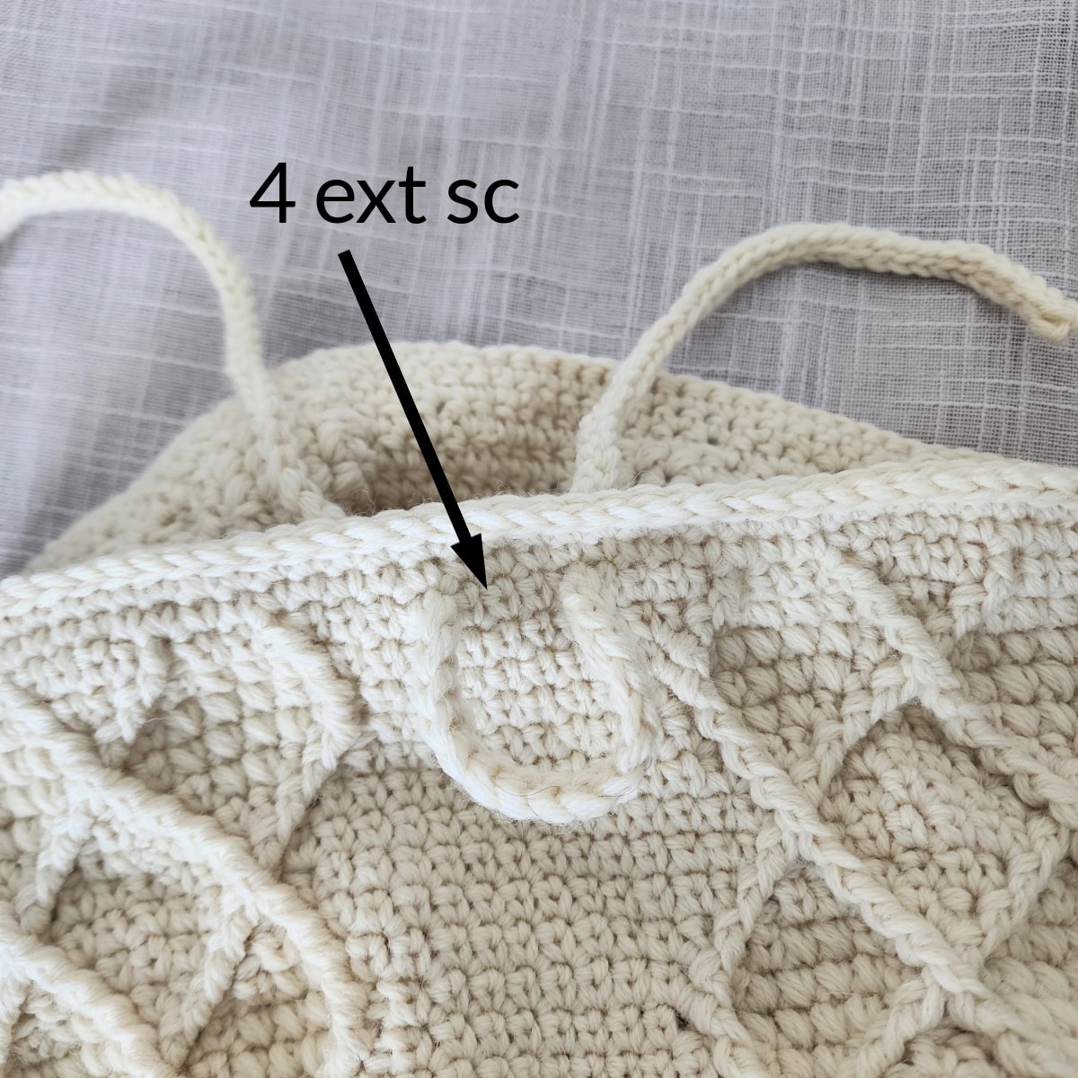 A cream colored crochet icord being woven in a crochet purse to create a pleat.