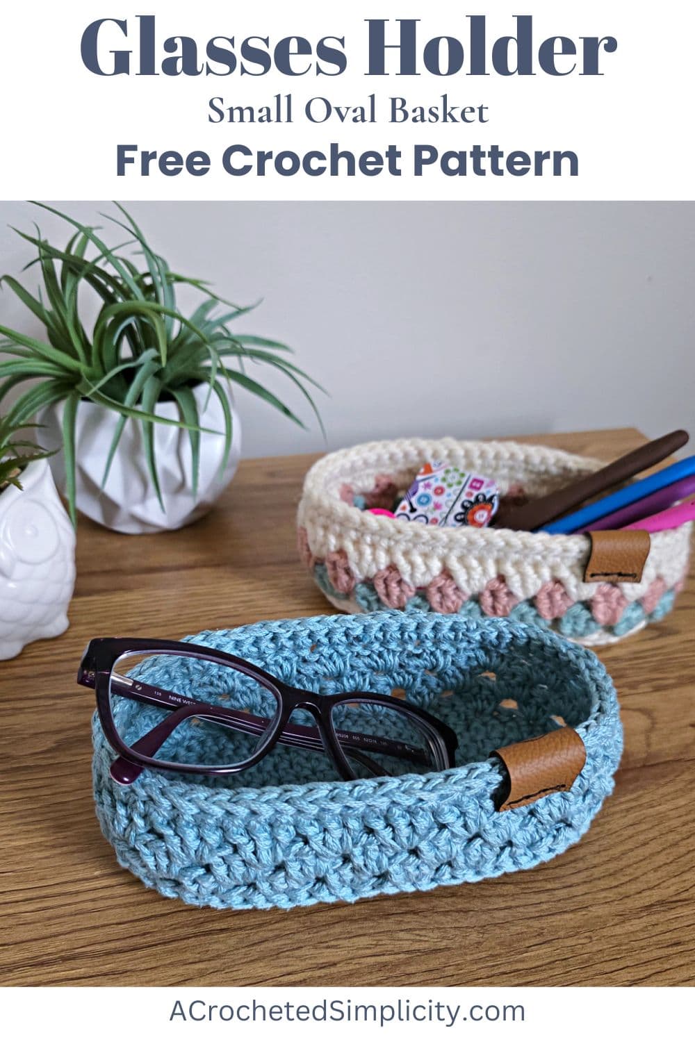 Two small crochet baskets, one for a glasses holder and one a crochet hook holder sitting on a wooden table.