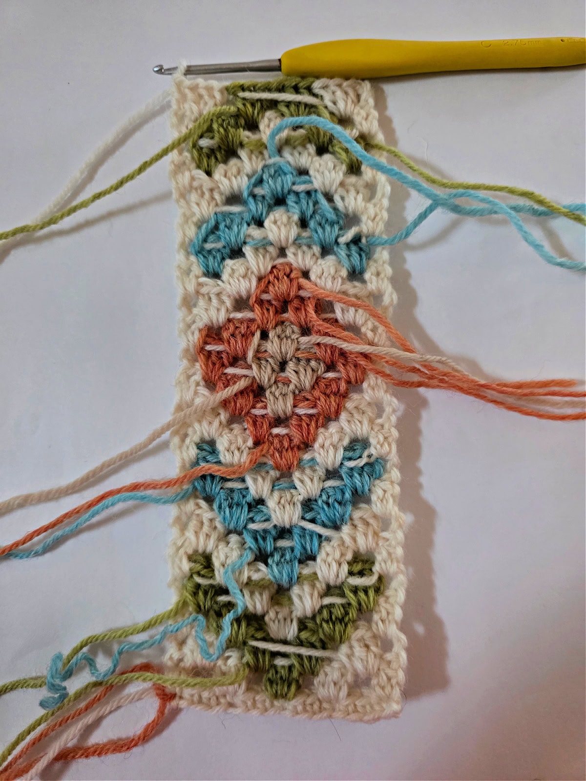 A crochet colorwork motif being made to edge a crochet scarf.